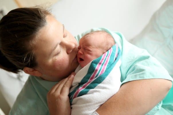 mom kissing new baby r