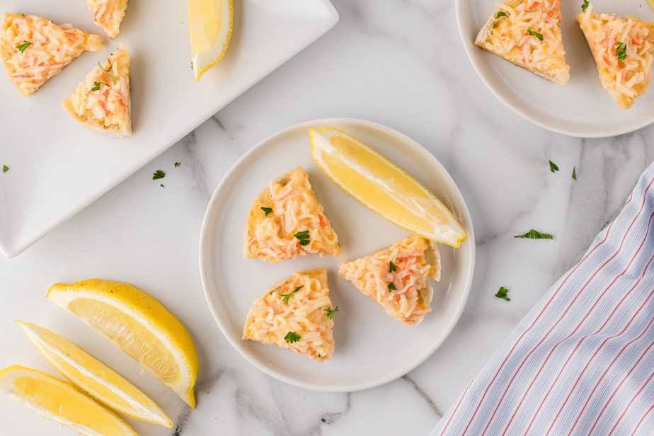 crabbies-english-muffin-crab-appetizer on white plate with lemon wedges