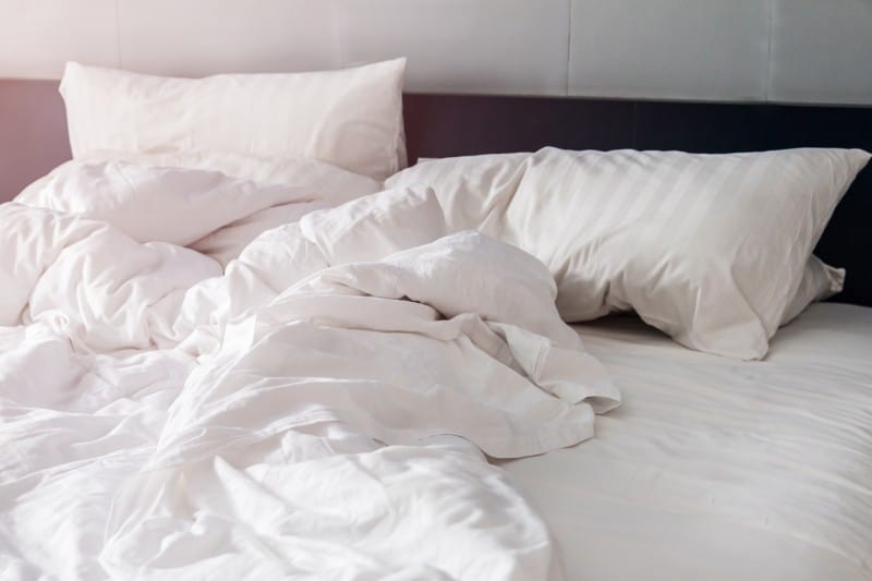 bed and white pillows with wrinkle blanket in bedroom,