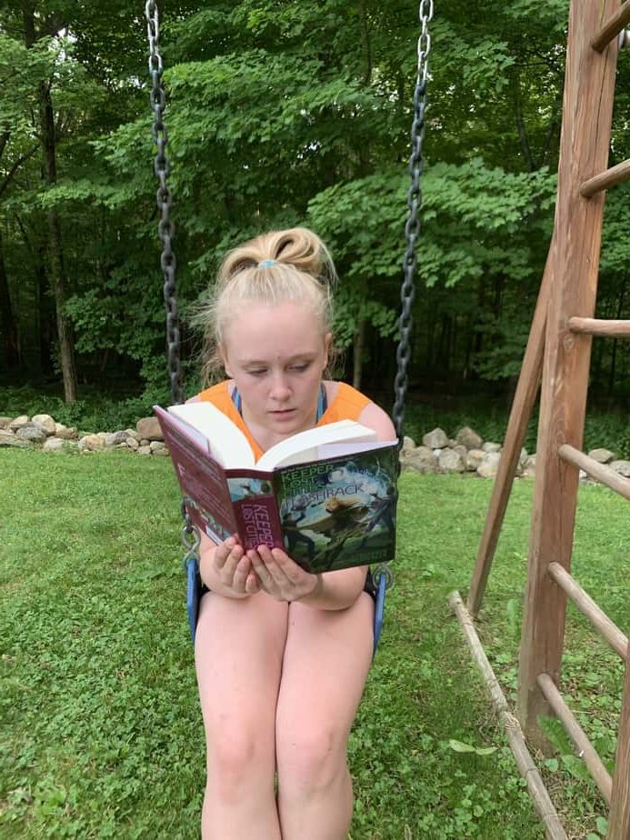 best summer reading books for kids girl reading on swing