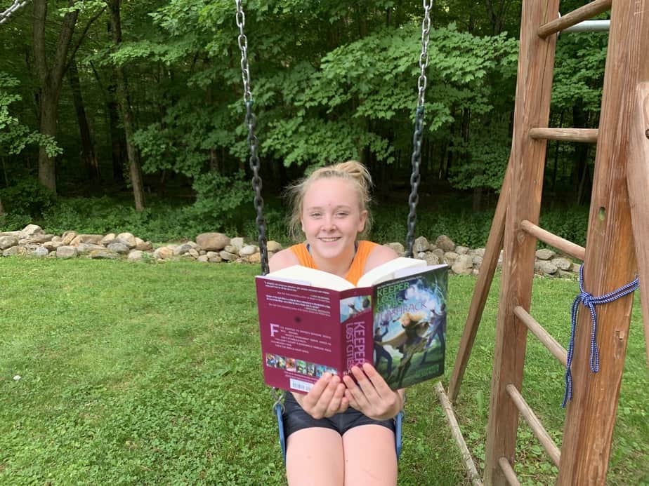 best summer reading books for kids girl reading on swing