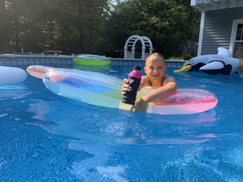 What to Look for in a Sports Drink for Kids girl swimming in pool holding Gatorade Bolt 24