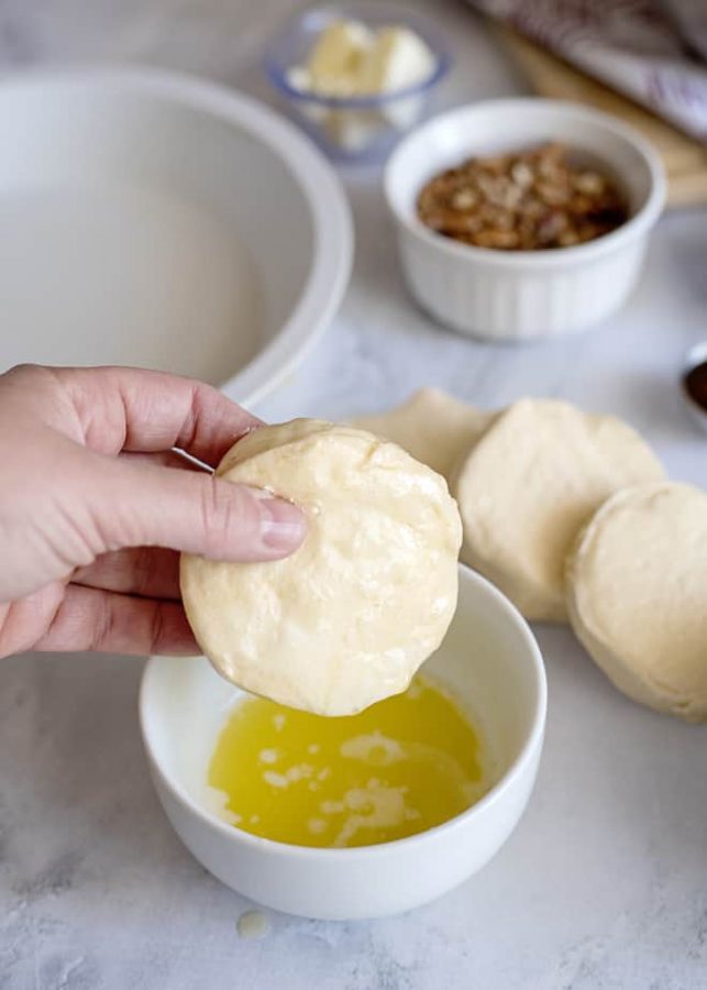 dipping biscuit into butter for sticky buns