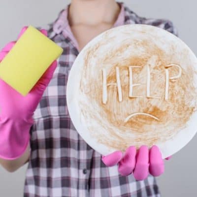 woman holding sponge with dirty plate that says help