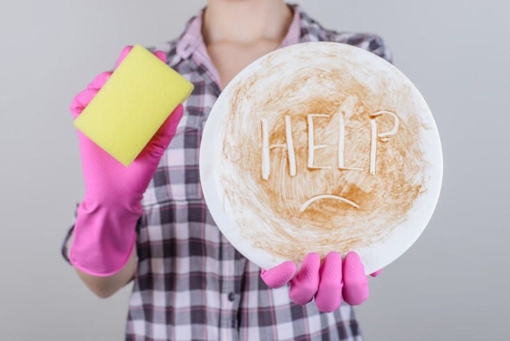 woman holding sponge with dirty plate that says help