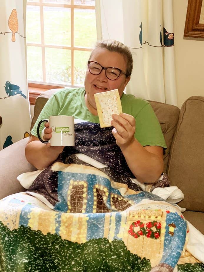 Woman holding pop tart and Gilmore girls night with blanket on lap