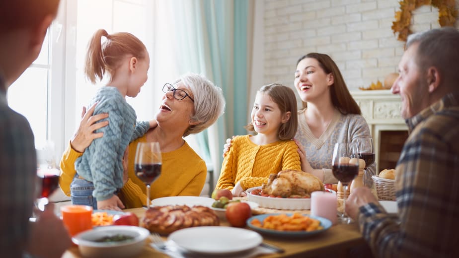 Happy Thanksgiving Day! Autumn feast. Family sitting at the table and celebrating holiday. Grandparents, mother, father and children. Traditional dinner.