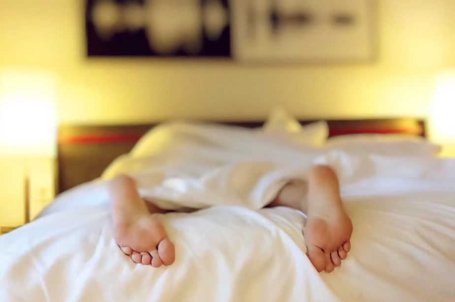 person lying on bed feet sticking out 