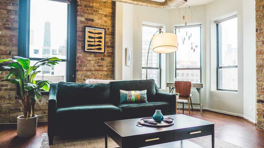 living room with brick accent wall and teal couch