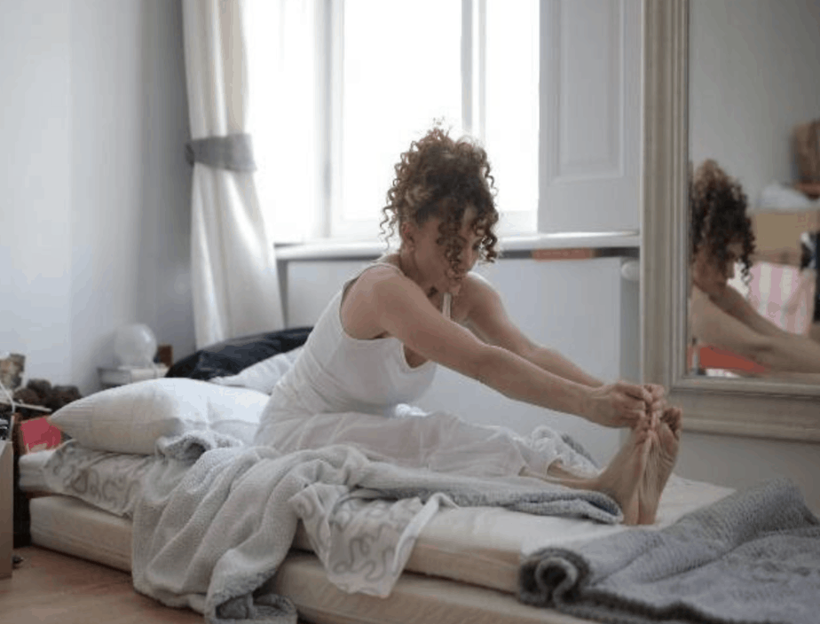 woman stretching on mattress on floor