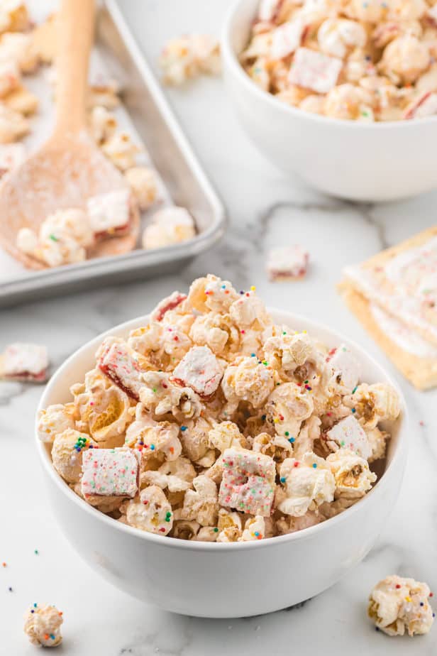 Strawberry glazed popcorn mixed with pop tart pieces in white bowl