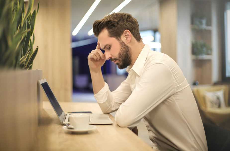 man with hand on temple working on laptop