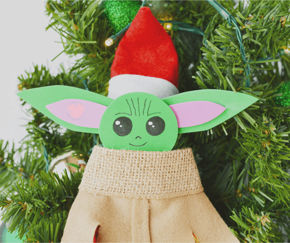 elf on the shelf with baby yoda costume and santa hat on a tree 