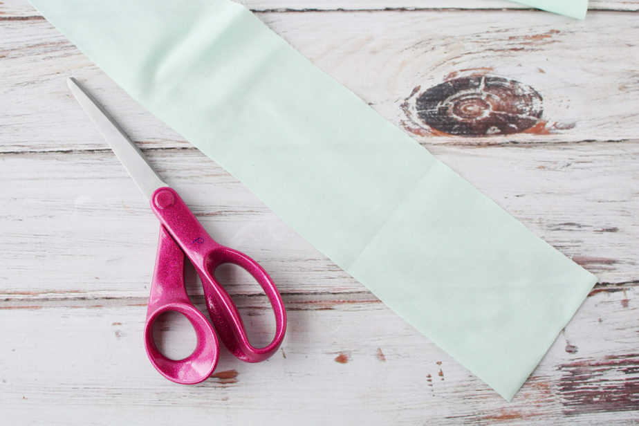 pink sewing scissors and light green fabric swatch