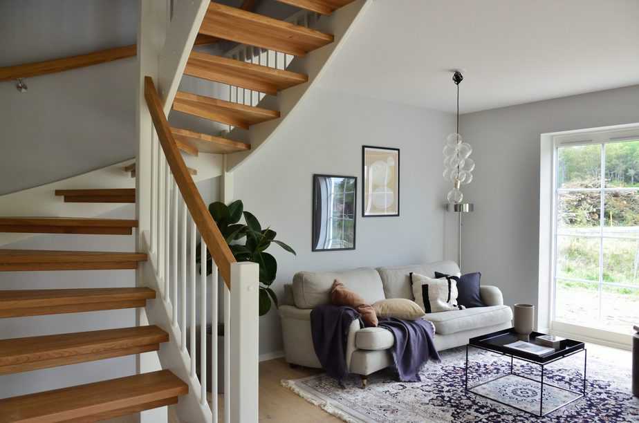 white couch near white and oak curved stairs 