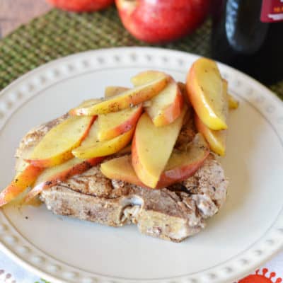 cooked pork chop topped with apples on white plate