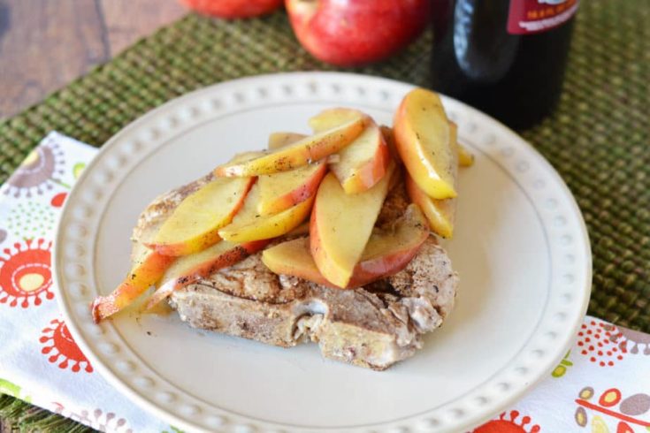 cooked pork chop topped with apples on white plate