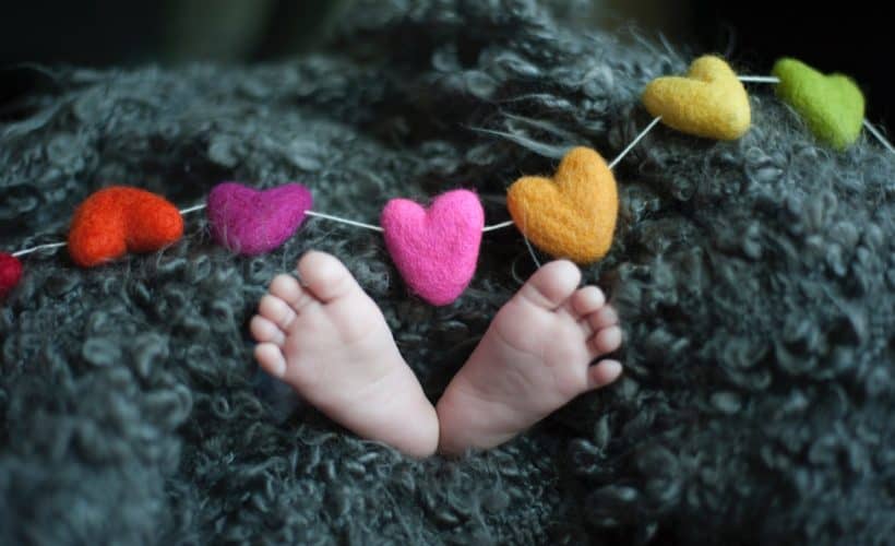 close up of baby feet with felt hearts on a garland