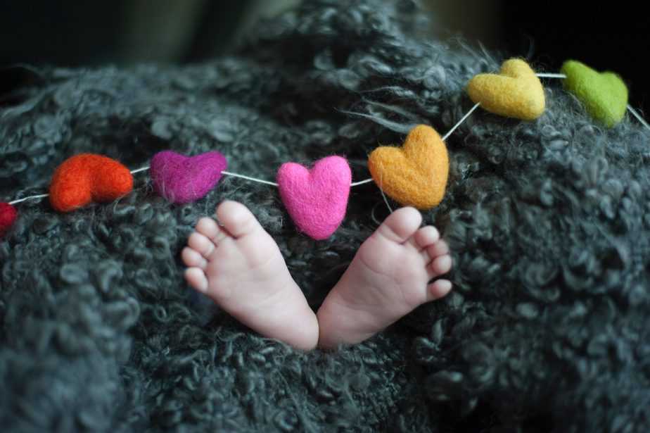 close up of baby feet with felt hearts on a garland