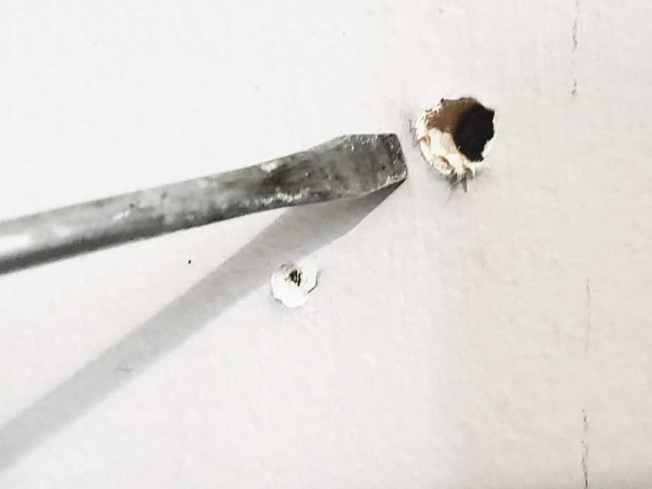 hole in drywall with screwdriver on side