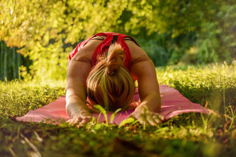woman on yoga mat in grass doing pose