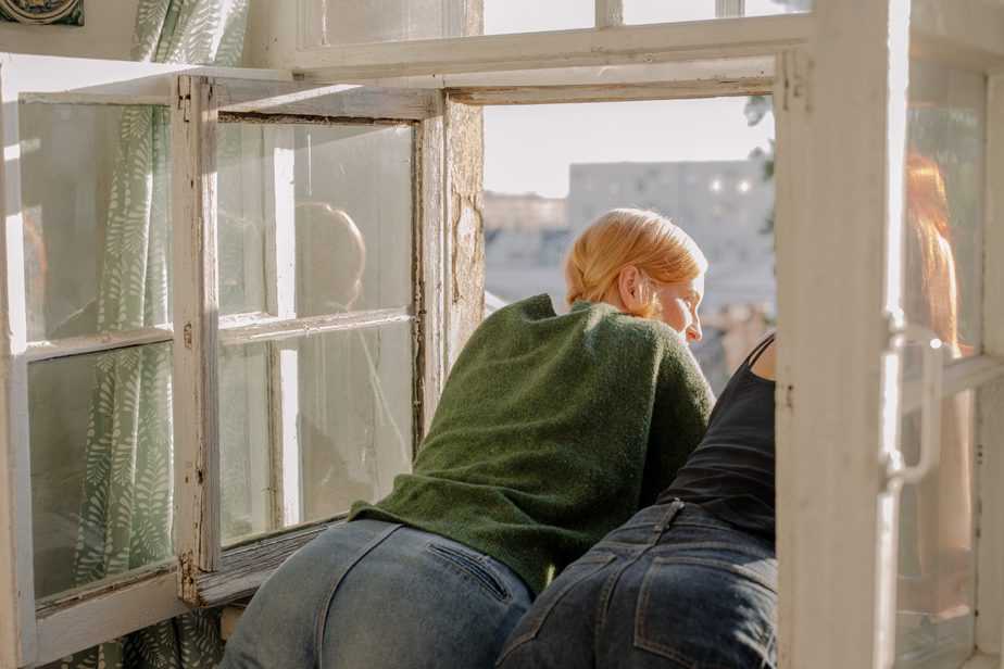 women in jeans looking out of open windows