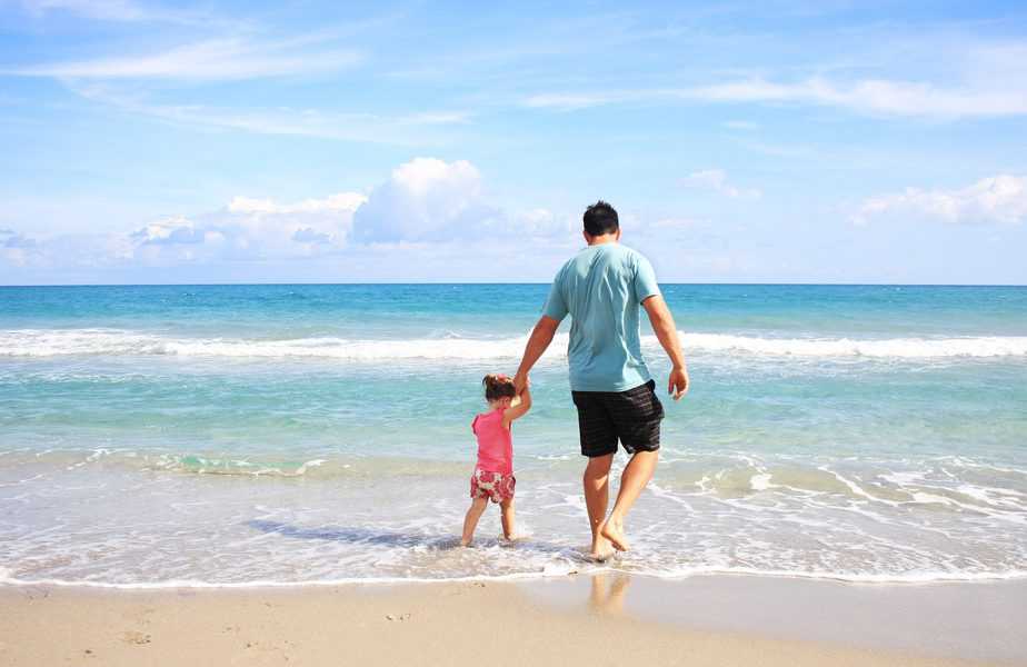 Ensure Your Next Trip Is One Everyone Can Enjoy dad and daughter holding hands walking into ocean