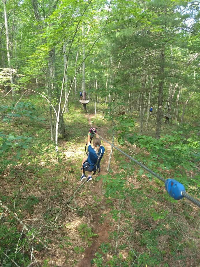 young teen ziplining in woods