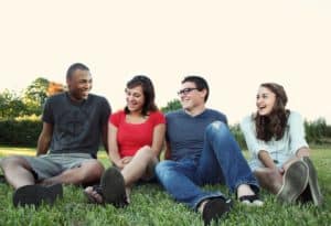 Smart Ways To Expand Your Social Circle Group of four adults of different races sitting together on grass smiling 
