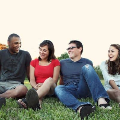 Smart Ways To Expand Your Social Circle Group of four adults of different races sitting together on grass smiling