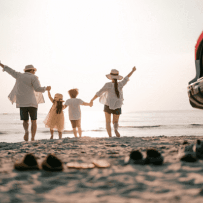 two adults with two kids holding hands at waters edge on a beach