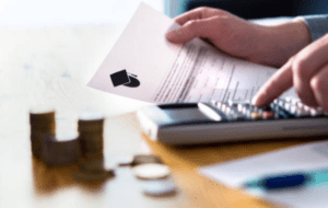 close up of someone doing paying an education bill using a calculator with a stack of coins on the table