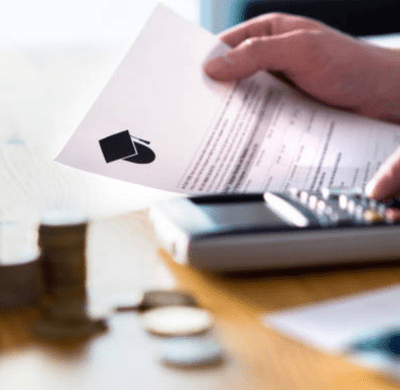 close up of someone doing paying an education bill using a calculator with a stack of coins on the table