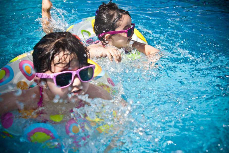 tips for travel with kids - 2 small girls swimming in a pool during the day