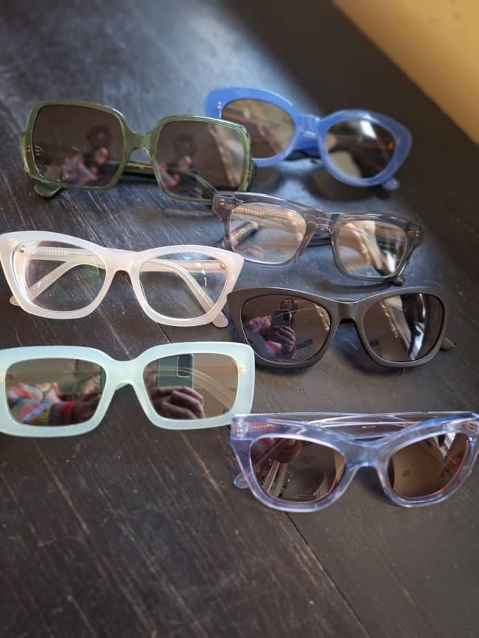 Several pairs of DL Eyewear glasses and sunglasses on a table