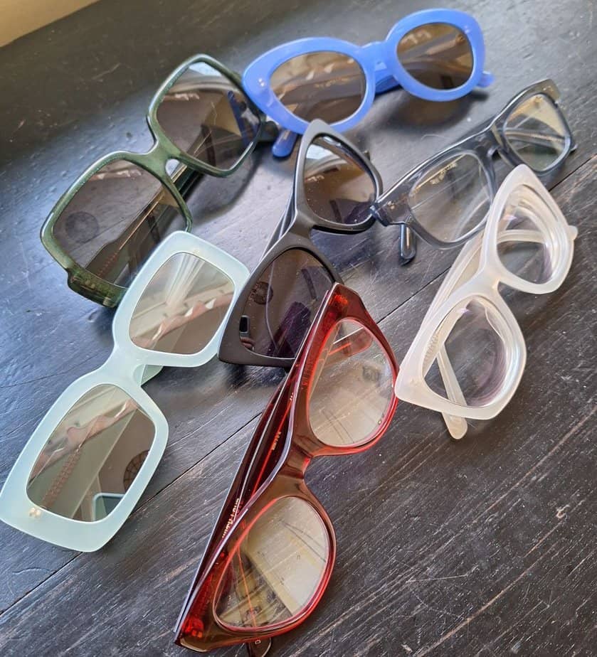 Several pairs of DL Eyewear glasses and sunglasses on a table