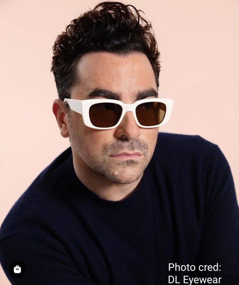 Image of Dan Levy wearing white sunglasses and black sweater